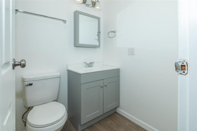 bathroom featuring baseboards, vanity, toilet, and wood finished floors