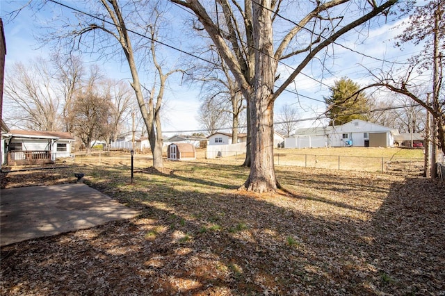 view of yard featuring an outbuilding, a storage unit, fence, and a residential view