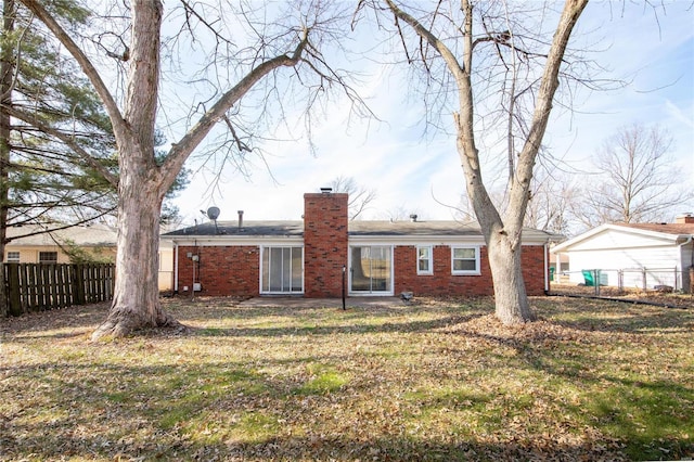 rear view of property with a yard, brick siding, fence, and a chimney