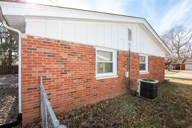 view of property exterior with board and batten siding, brick siding, and central air condition unit