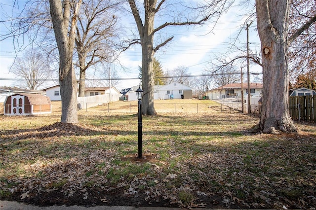 view of yard featuring a storage unit, a residential view, fence, and an outbuilding