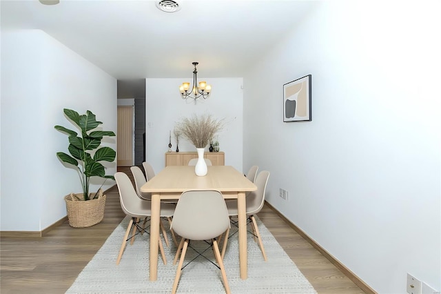 dining space featuring light wood-style floors, baseboards, visible vents, and a chandelier