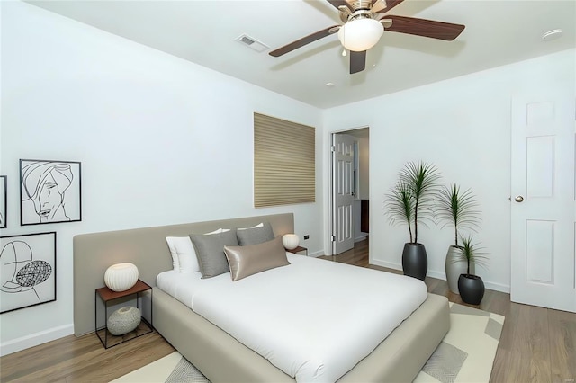 bedroom with baseboards, visible vents, ceiling fan, and wood finished floors