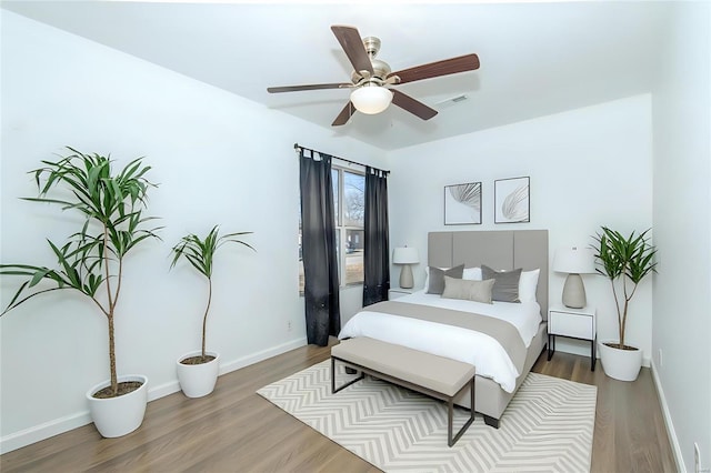 bedroom with visible vents, ceiling fan, baseboards, and wood finished floors