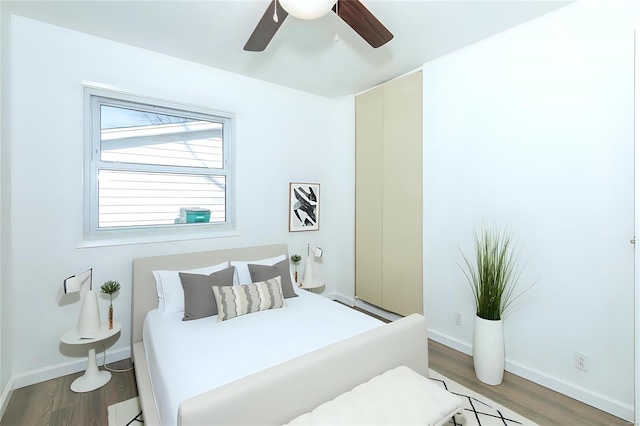 bedroom with a ceiling fan, baseboards, and wood finished floors