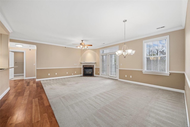 unfurnished living room with hardwood / wood-style floors, crown molding, a healthy amount of sunlight, and ceiling fan with notable chandelier