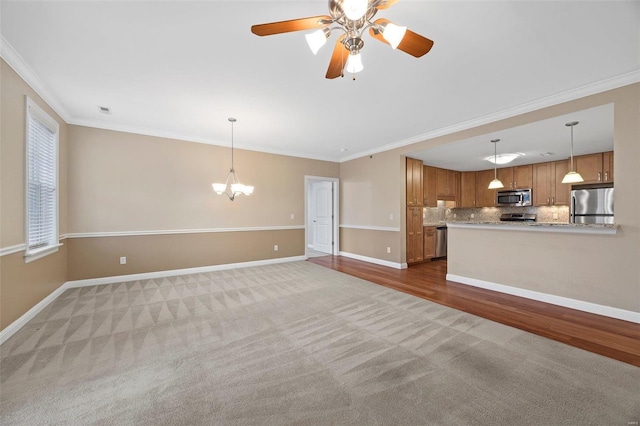 unfurnished living room featuring crown molding, light colored carpet, and ceiling fan with notable chandelier