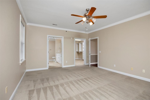 unfurnished bedroom with ornamental molding, a walk in closet, light colored carpet, ensuite bath, and a closet