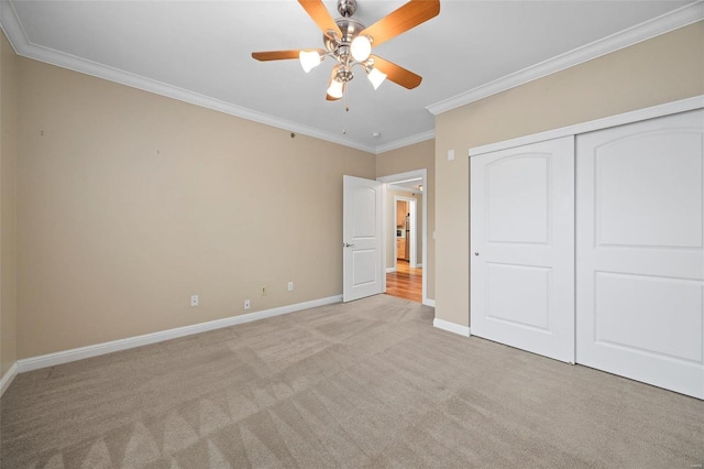 unfurnished bedroom with ceiling fan, light colored carpet, ornamental molding, and a closet