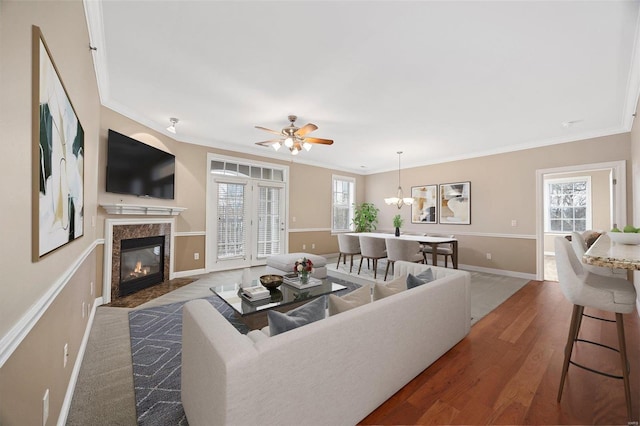 living room featuring a premium fireplace, ornamental molding, dark hardwood / wood-style floors, and a healthy amount of sunlight