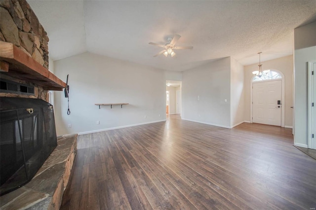 unfurnished living room featuring a fireplace, a textured ceiling, dark hardwood / wood-style flooring, ceiling fan with notable chandelier, and vaulted ceiling