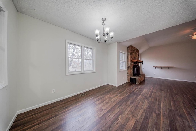 unfurnished living room with lofted ceiling, an inviting chandelier, a textured ceiling, and dark hardwood / wood-style flooring