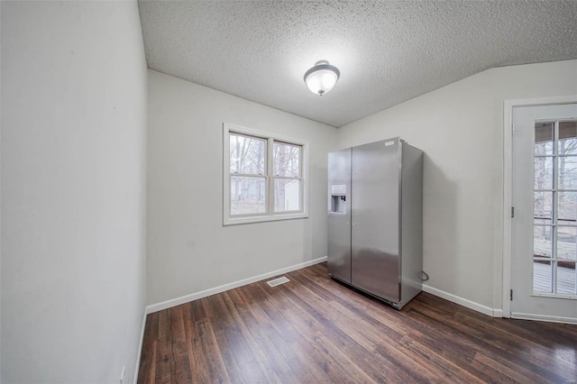 interior space featuring dark wood-type flooring, stainless steel fridge, and a textured ceiling