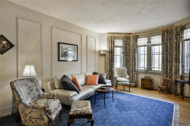 living area with a textured wall, wood finished floors, and baseboards