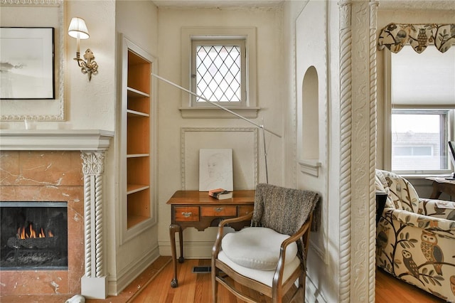 sitting room with visible vents, a fireplace, wood finished floors, and a wealth of natural light