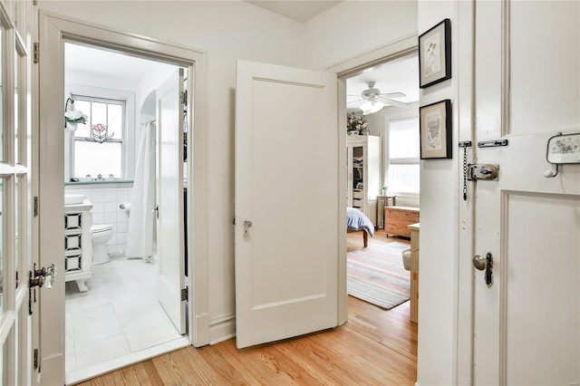 hallway featuring light wood-style flooring and tile walls