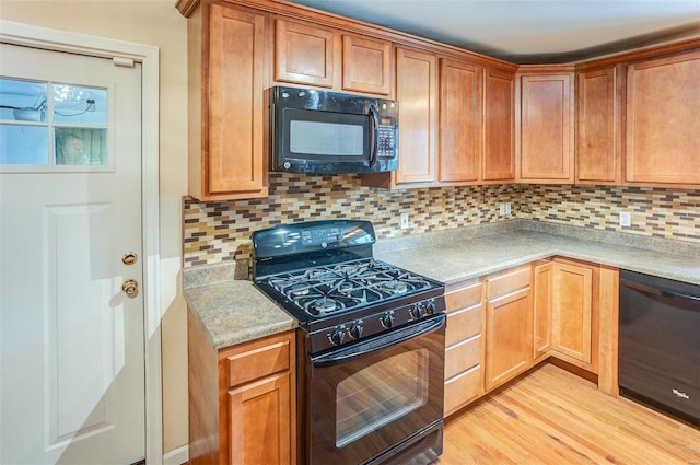 kitchen with light hardwood / wood-style floors, decorative backsplash, and black appliances