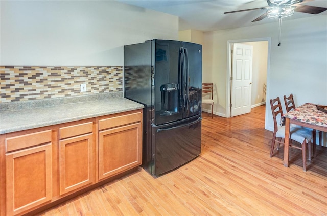 kitchen with tasteful backsplash, light hardwood / wood-style flooring, ceiling fan, and black fridge