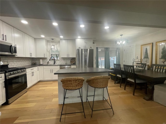 kitchen with white cabinetry, appliances with stainless steel finishes, and decorative light fixtures