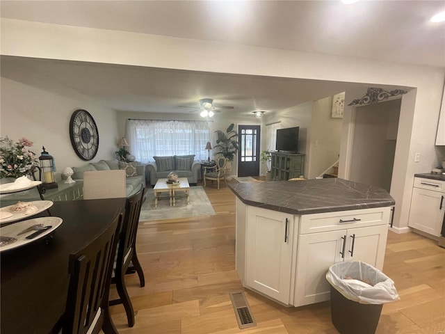 kitchen with ceiling fan, a center island, white cabinets, and light wood-type flooring