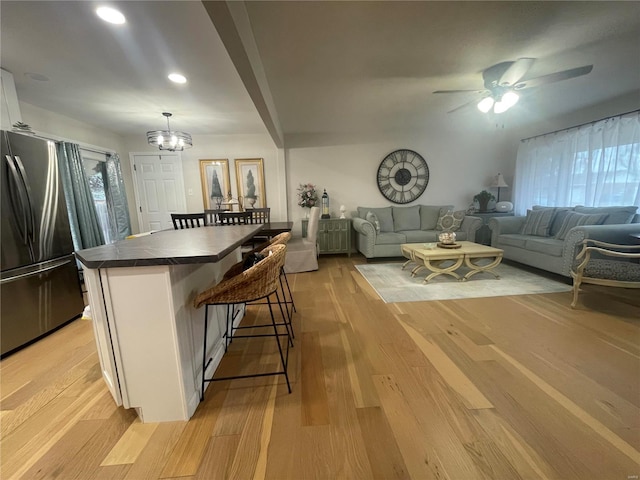 kitchen with white cabinetry, a breakfast bar, stainless steel refrigerator, and light hardwood / wood-style floors