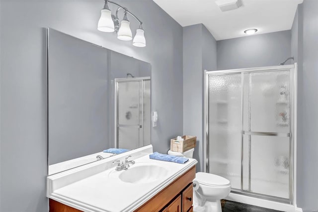 bathroom with a shower with door, vanity, and toilet