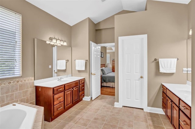 bathroom featuring tile patterned flooring, vanity, vaulted ceiling, and a tub