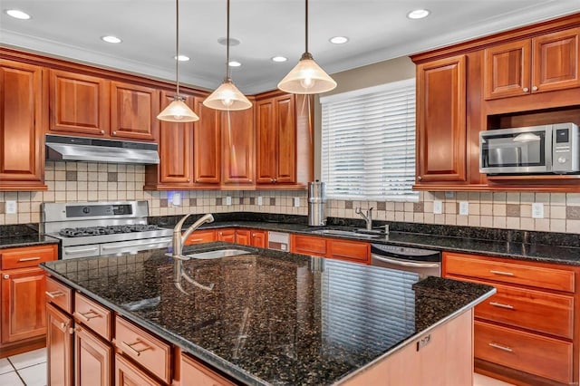 kitchen featuring sink, dark stone countertops, appliances with stainless steel finishes, pendant lighting, and a kitchen island with sink