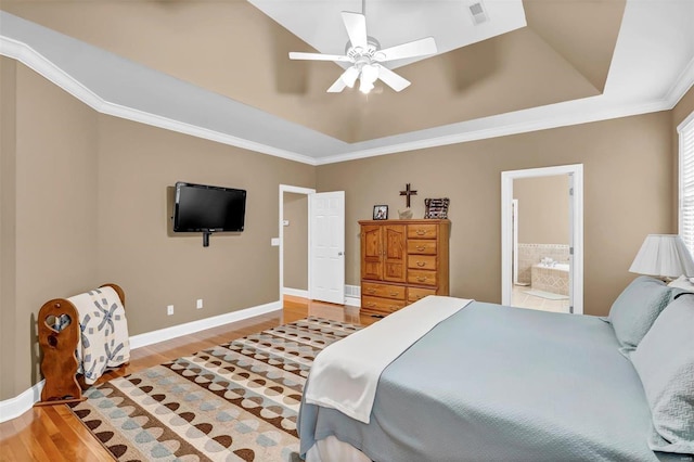 bedroom with crown molding, ensuite bath, a raised ceiling, ceiling fan, and hardwood / wood-style floors