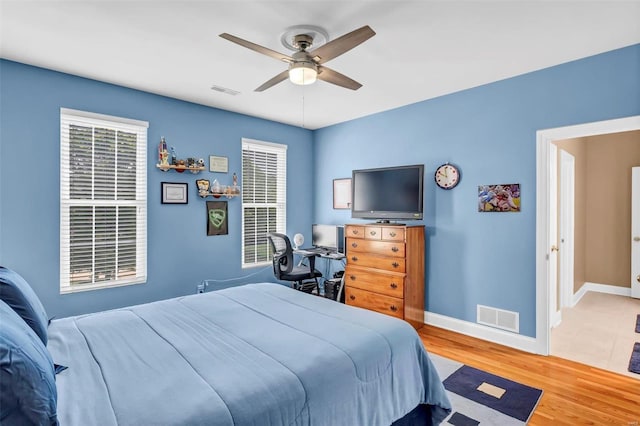 bedroom with multiple windows, hardwood / wood-style floors, and ceiling fan