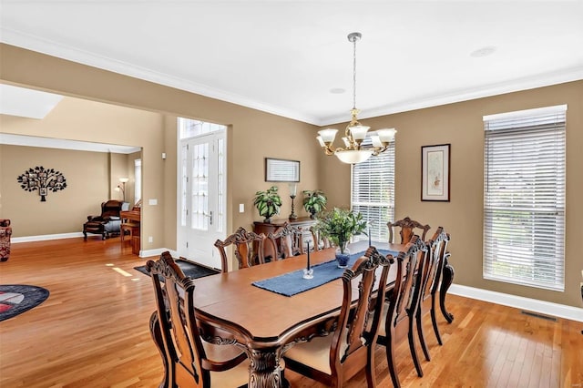 dining space with crown molding, a healthy amount of sunlight, and light hardwood / wood-style flooring