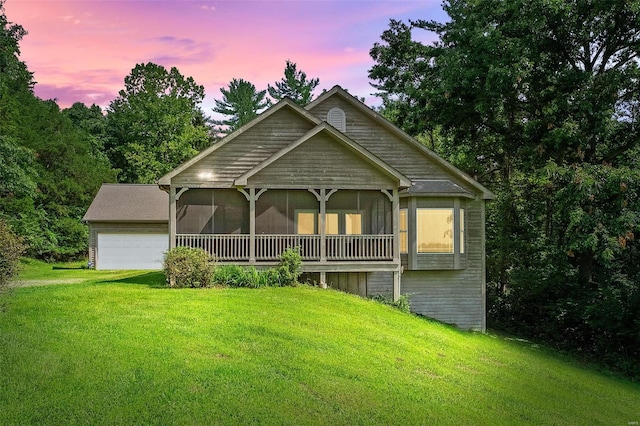 view of front facade with a garage, a sunroom, and a lawn