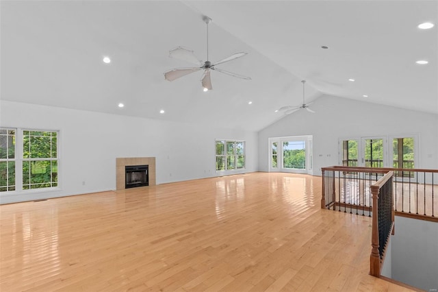 unfurnished living room with ceiling fan, a fireplace, high vaulted ceiling, and light hardwood / wood-style flooring