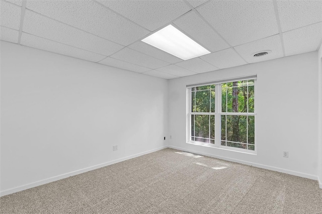 carpeted empty room featuring a drop ceiling