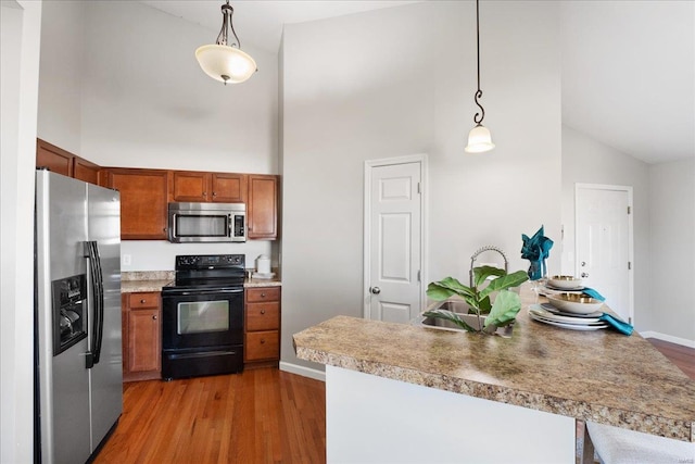 kitchen with decorative light fixtures, high vaulted ceiling, hardwood / wood-style flooring, and appliances with stainless steel finishes