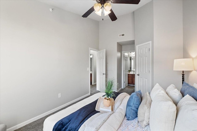 bedroom featuring ceiling fan, connected bathroom, high vaulted ceiling, and dark colored carpet