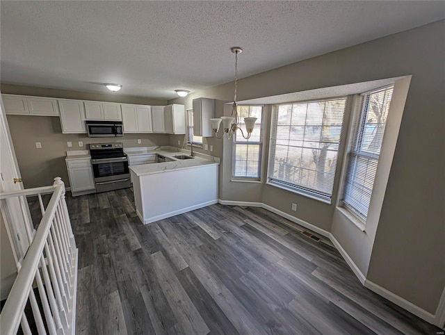 kitchen featuring decorative light fixtures, white cabinets, stainless steel appliances, dark wood-type flooring, and an inviting chandelier