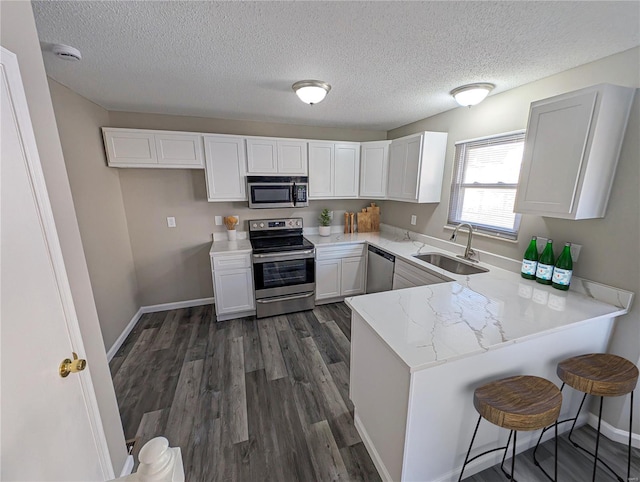 kitchen featuring sink, a breakfast bar area, kitchen peninsula, stainless steel appliances, and white cabinets