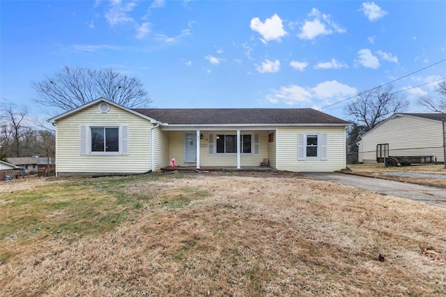 ranch-style home featuring covered porch and a front lawn