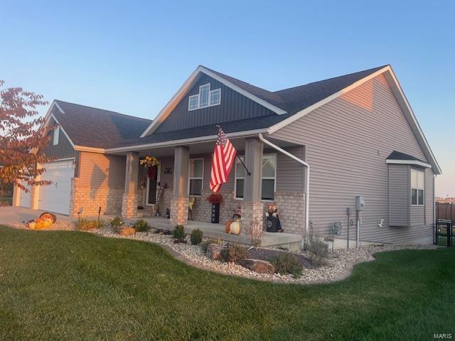 view of front of property featuring a garage, covered porch, and a front yard