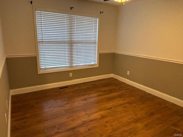 empty room with dark hardwood / wood-style floors and ceiling fan