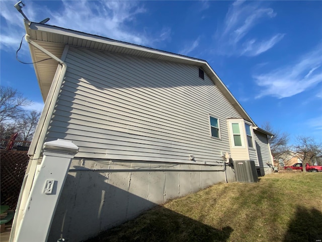 view of side of home featuring a lawn and central air condition unit