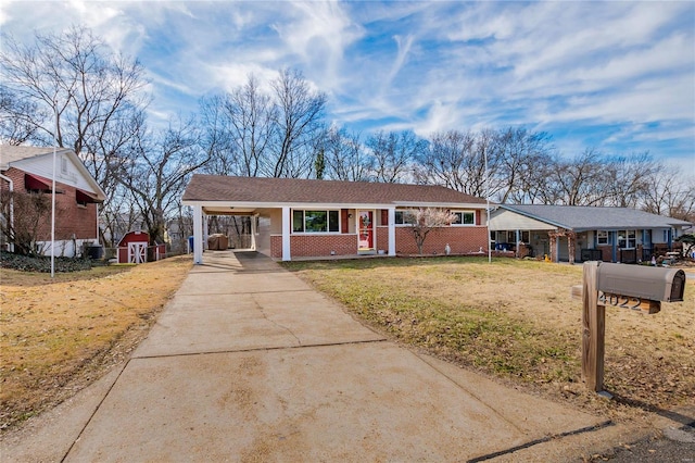 ranch-style home featuring a carport, a porch, a front yard, and a storage unit