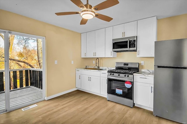 kitchen with light wood-type flooring, stainless steel appliances, sink, and white cabinets