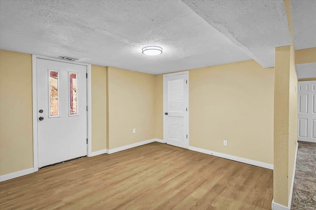 unfurnished room featuring a textured ceiling and light wood-type flooring