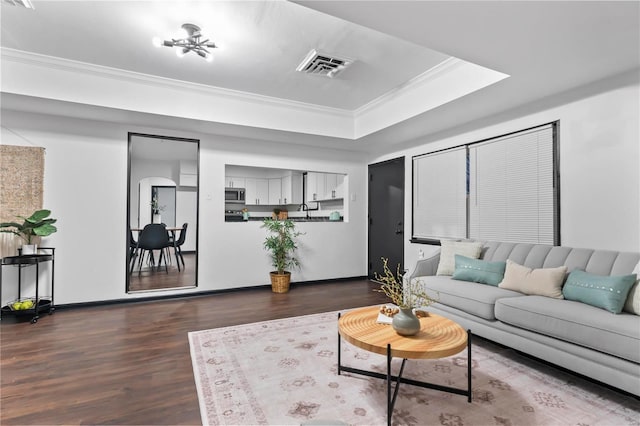 living room featuring ornamental molding, dark wood-type flooring, and a tray ceiling