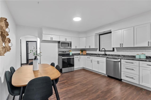 kitchen with tasteful backsplash, sink, white cabinets, and appliances with stainless steel finishes