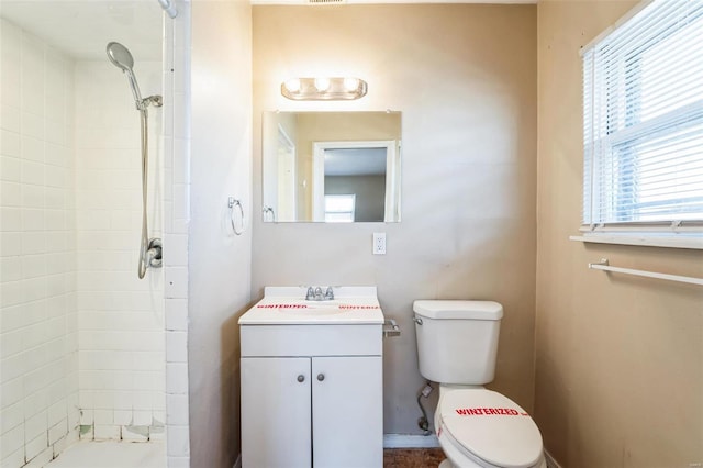 bathroom featuring vanity, toilet, and a tile shower