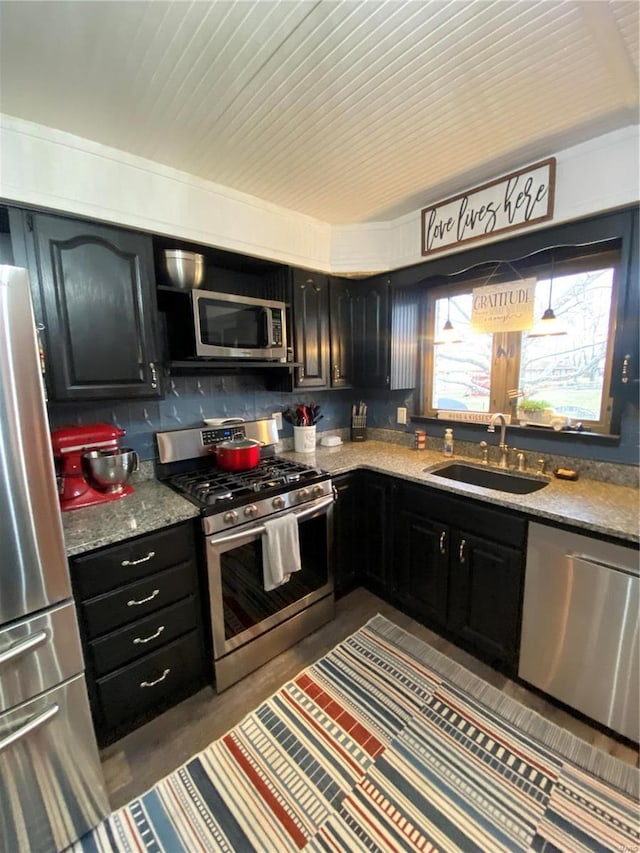 kitchen with appliances with stainless steel finishes, sink, and light stone counters