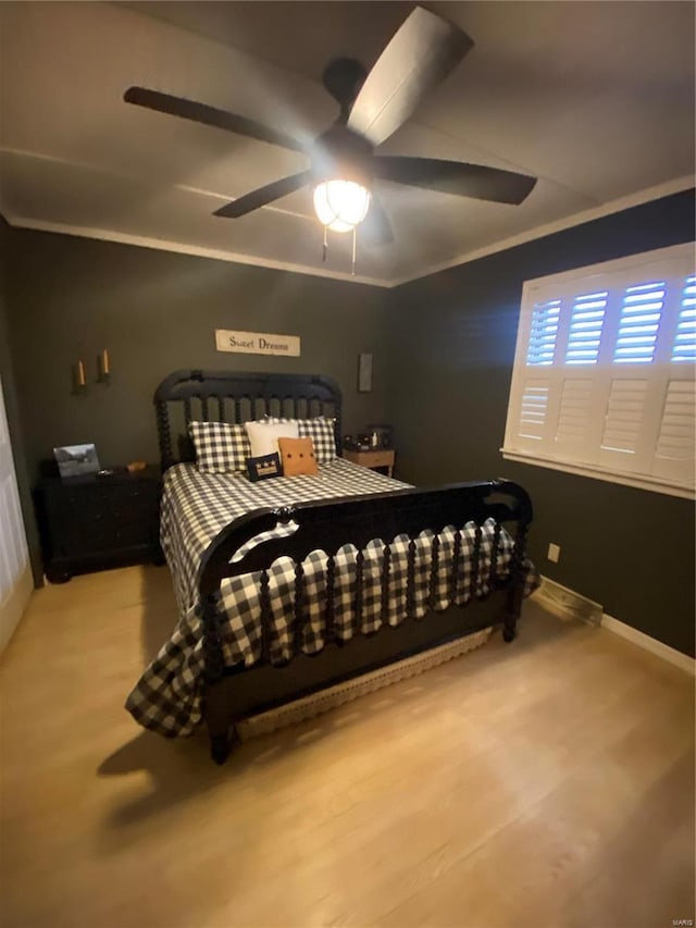 bedroom featuring hardwood / wood-style flooring, ornamental molding, and ceiling fan